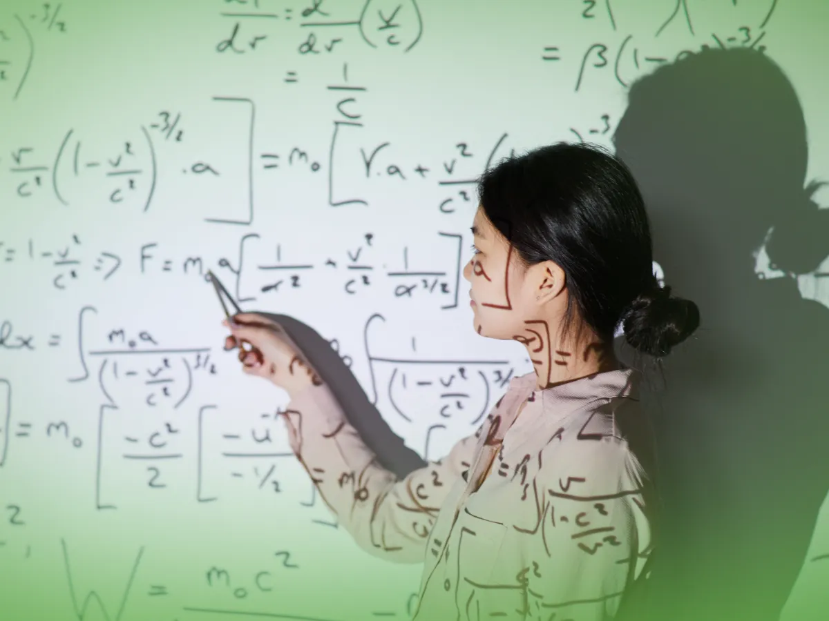 Mulher ensinando, apontando para fórmulas matemáticas complexas projetadas em um quadro.
Nome do Produto: Explicações de Matemática Aplicada 12.º Ano . Mensalidades