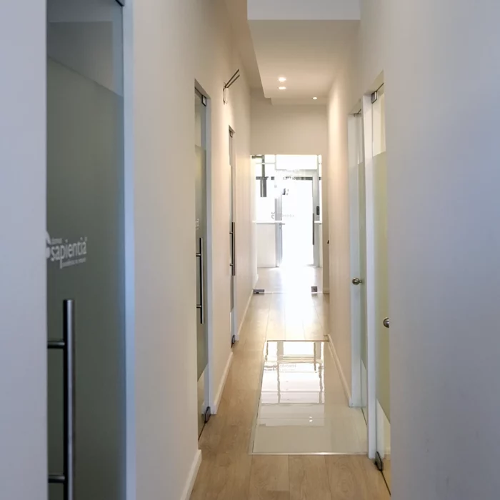 Corredor de um escritório com paredes brancas e portas de vidro.