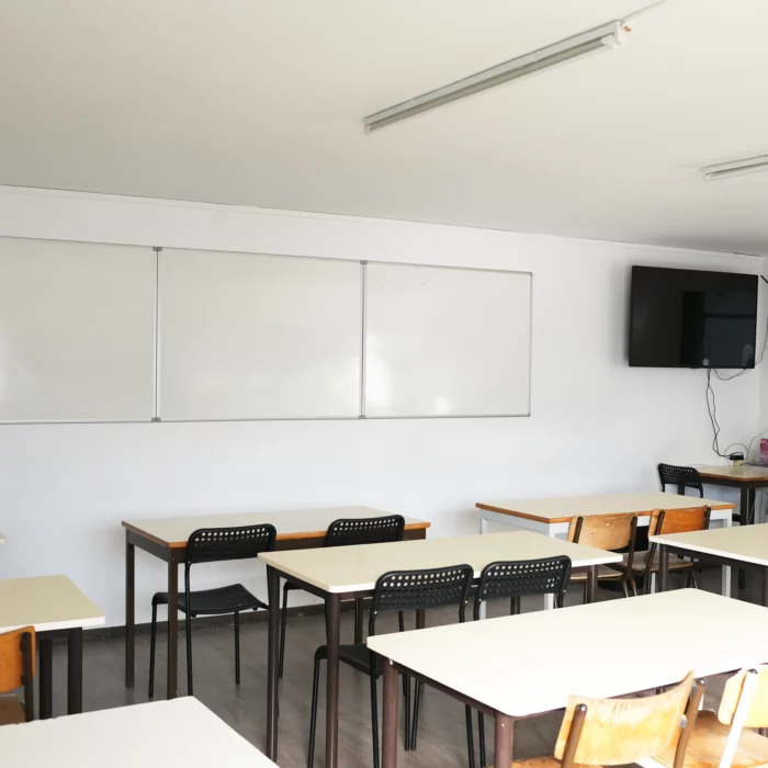 Uma sala de aula com mesas e quadro branco.