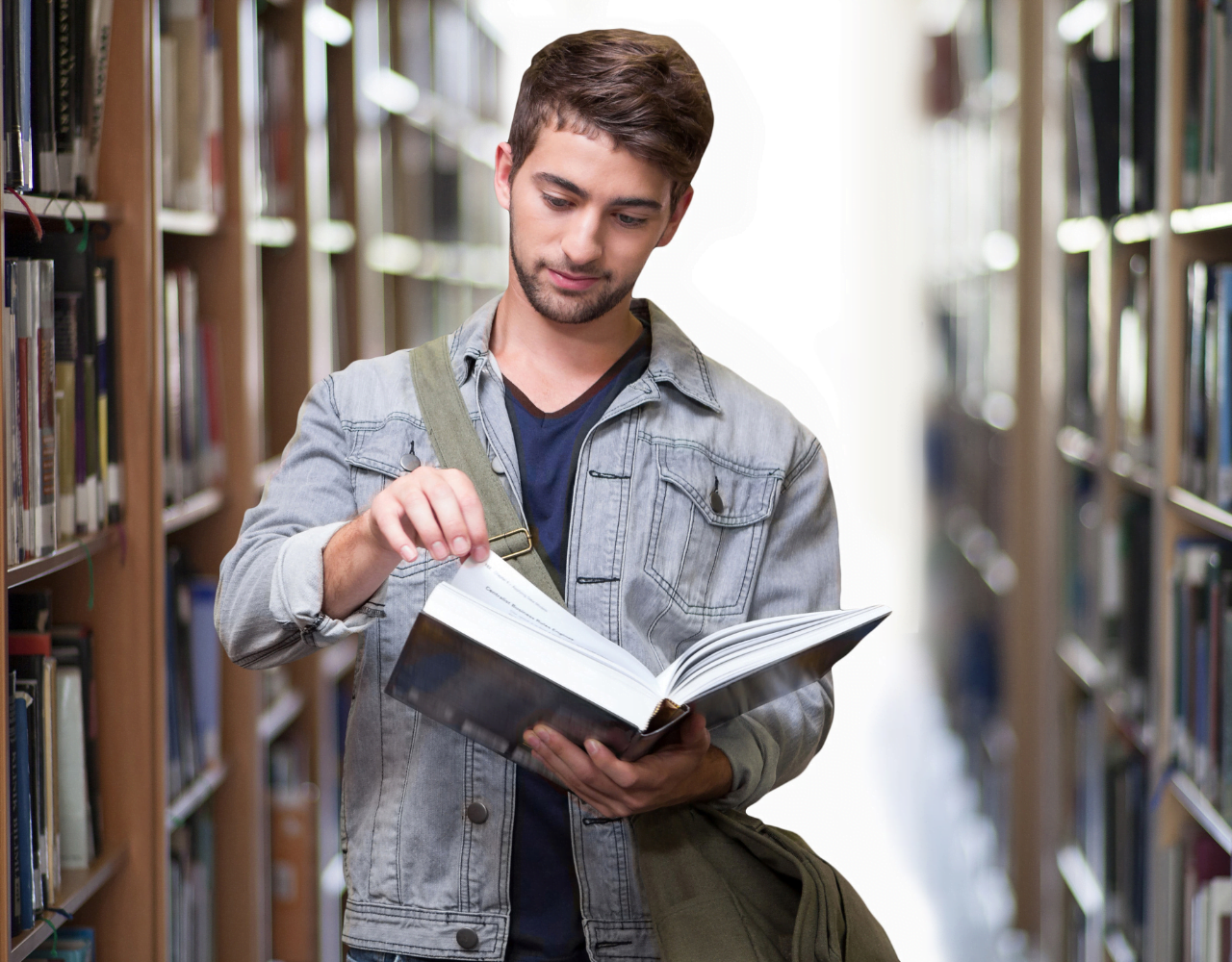 Um jovem lendo um livro em uma biblioteca.