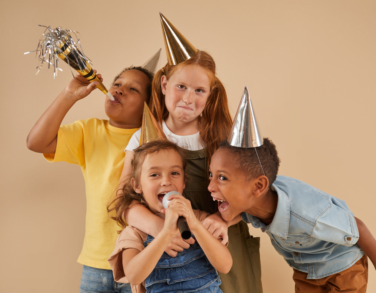 Um grupo de crianças com chapéus de festa segurando um microfone.