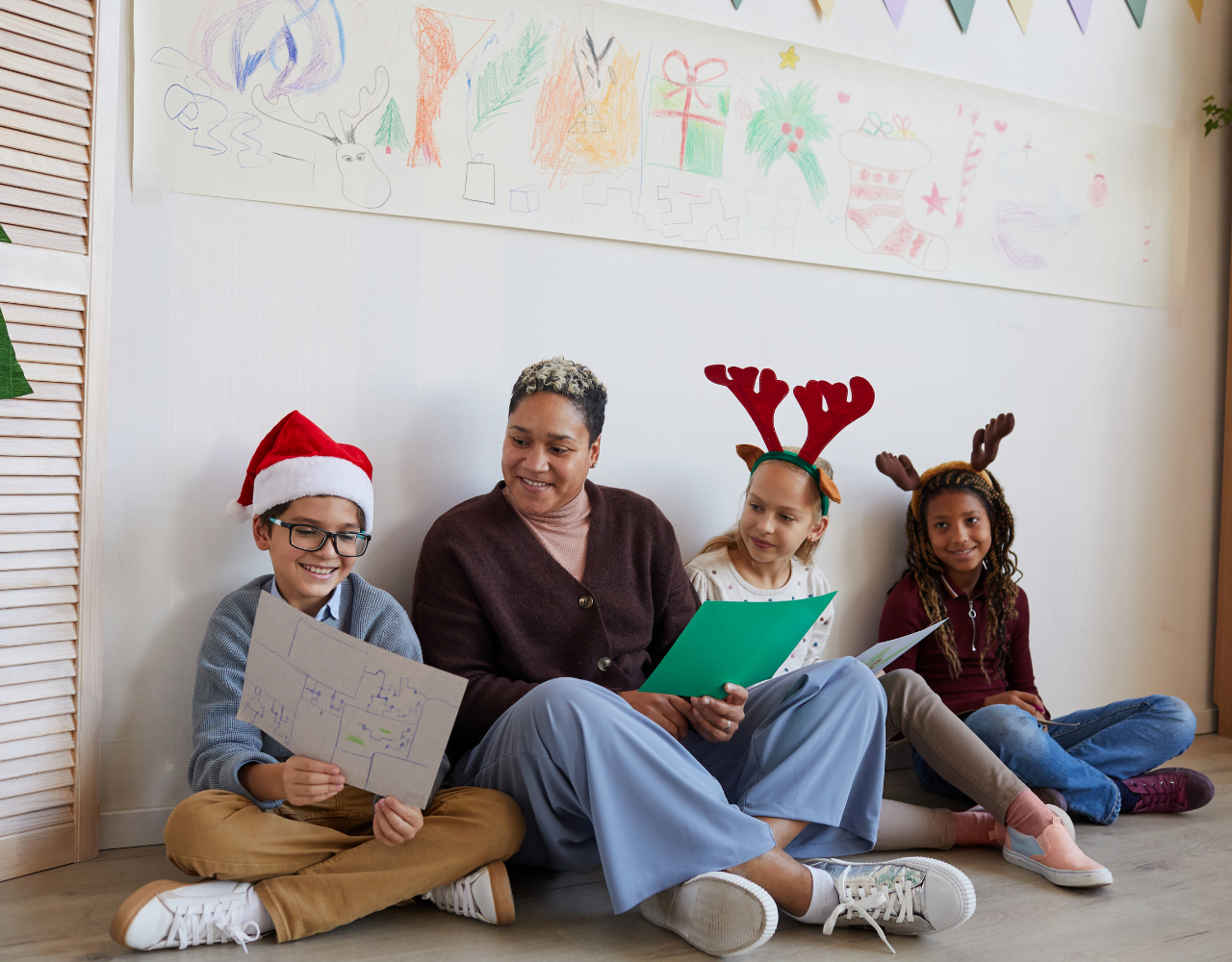 Um grupo de crianças usando chapéus de Natal sentados no chão.