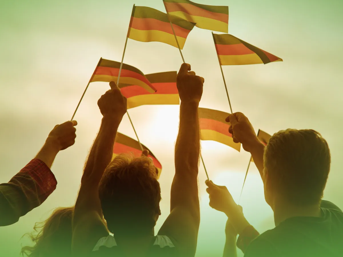 As pessoas estão levantando várias pequenas Explicações de Alemão 11.º Ano. Pacote de Horas contra um céu claro e nublado.