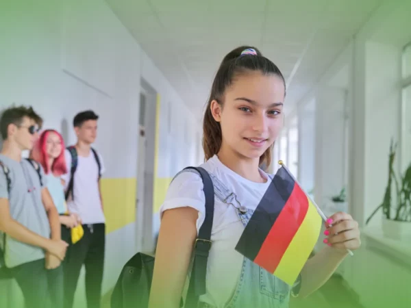Adolescente segura Explicações de Alemão 7.º Ano. Pacote de Horas no corredor da escola, com três colegas conversando ao fundo.