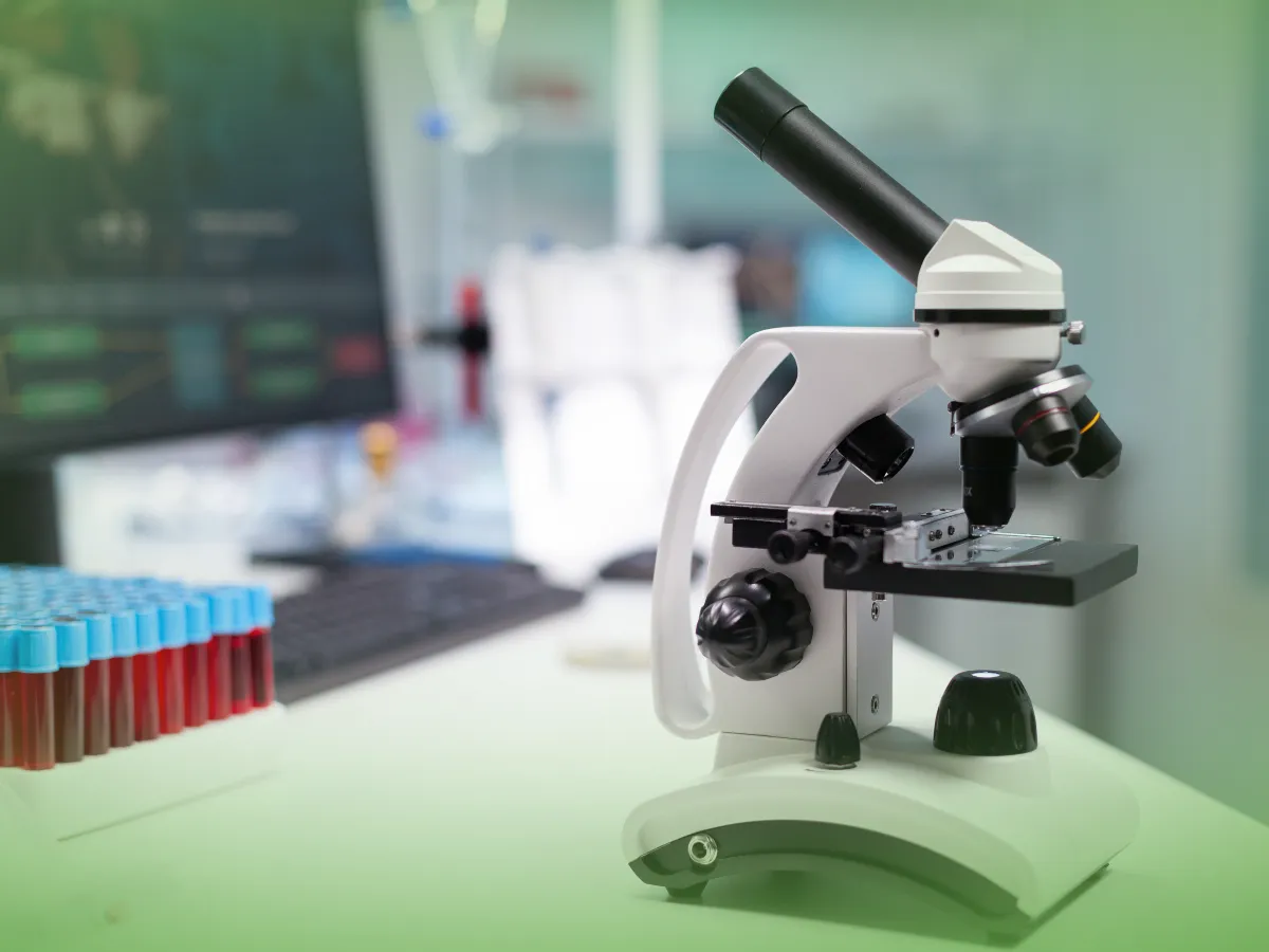 A Explicações de Bioquímica UN no laboratório com tubos de ensaio ao fundo, representando um ambiente de pesquisa científica.