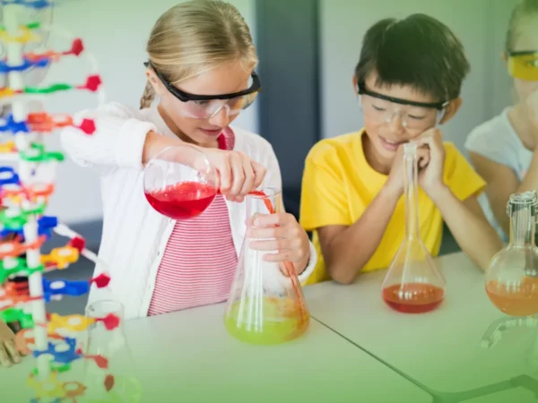 Duas crianças num laboratório de ciências, uma rapariga a deitar líquido vermelho num frasco enquanto um rapaz observa, ambos usando óculos de segurança com Explicações de Ciências Naturais 5.º Ano. Pacote de Horas.