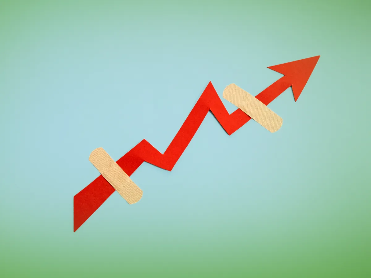 Uma seta vermelha com tendência ascendente com dois band-aids, em um fundo azul-petróleo, simbolizando recuperação ou cura em andamento.