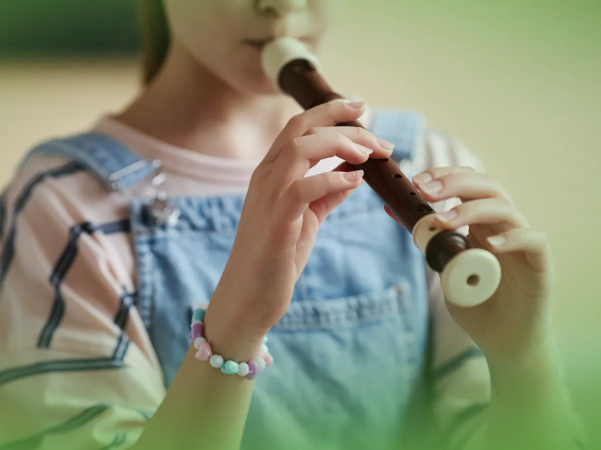 Uma jovem tocando Explicações de Educação Musical 5.º Ano. Pacote de Horas, focando atentamente no posicionamento dos dedos no instrumento.