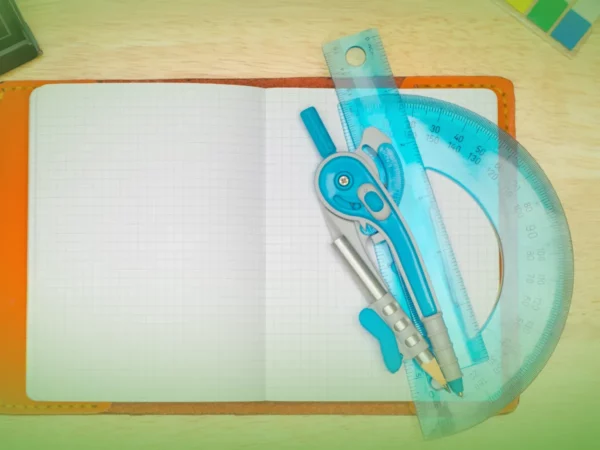 Open Explicações de Educação Visual 8.º Ano . Pacote de Horas com grade de papel milimetrado, com bússola, transferidor e régua sobre mesa de madeira. Tons de cores quentes e bem iluminados.