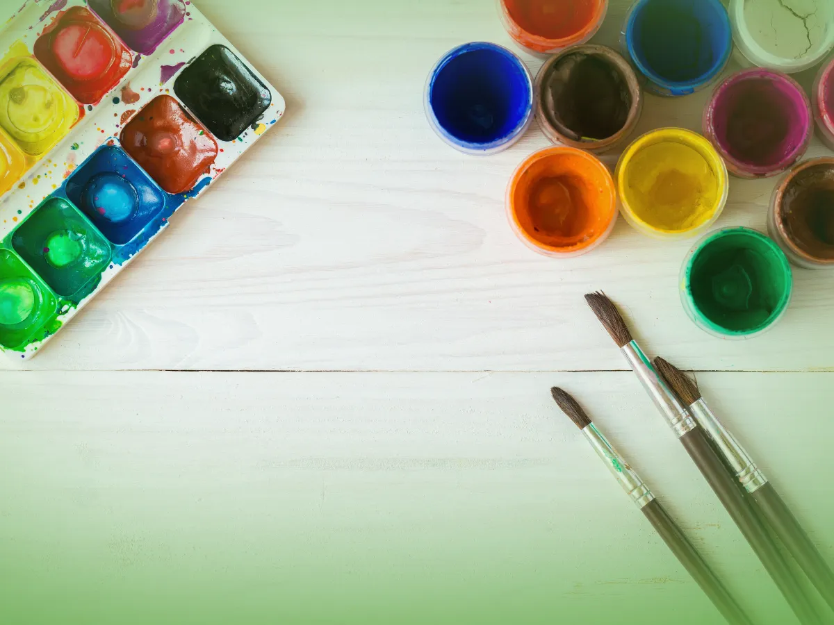 Explicações de Educação Visual 9.º Ano . Pacote de Horas e pincéis sobre superfície de madeira branca, prontos para um projeto de arte.