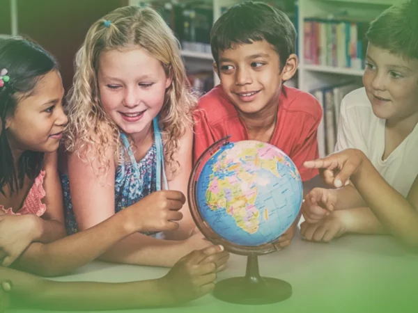 Quatro crianças de diversas origens interagem com Explicações de Estudo do Meio 2.º Ano, Pacote de Horas em sala de aula, demonstrando curiosidade e prazer.