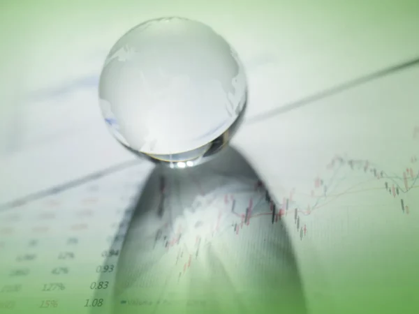 Uma bola de cristal transparente repousa nas Explicações de Finanças da ONU. Pacote de Horas com foco nas linhas e números borrados na esfera.