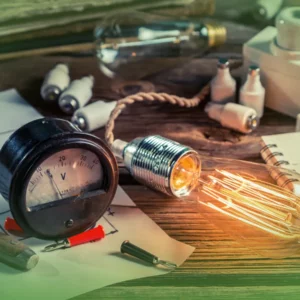 Equipamento elétrico antigo, incluindo voltímetro, lâmpadas e esboços em uma mesa de madeira, destacando uma configuração de engenharia da velha escola com Explicações de Física Geral UN. Pacote de Horas.