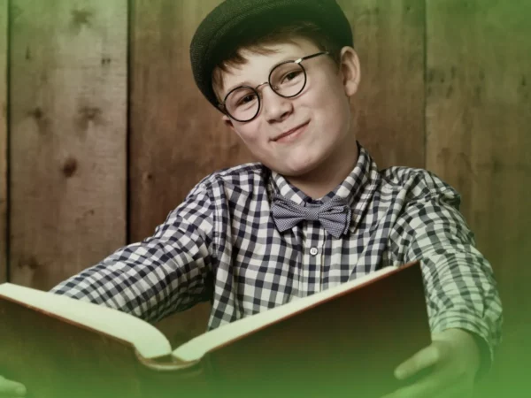 Um menino de óculos, gravata borboleta e boné sorri enquanto lê um livro em um cenário de madeira. Explicações de História 7.º Ano . Pacote de Horas