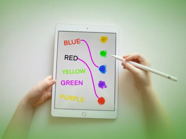 Uma pessoa detém Explicações de Inglês 3.º Ano . Pacote de Horas exibindo nomes de cores combinados com pontos coloridos, usando uma caneta para interagir com a tela.