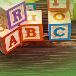 Colorido Explicações de Língua Portuguesa 1.º Ano . Blocos Pacote de Horas espalhados sobre uma superfície de madeira verde, destacando letras como a, b e c.