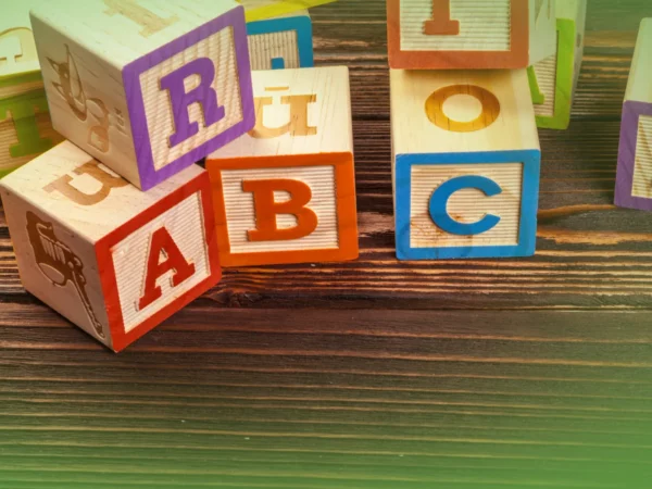 Colorido Explicações de Língua Portuguesa 1.º Ano . Blocos Pacote de Horas espalhados sobre uma superfície de madeira verde, destacando letras como a, b e c.