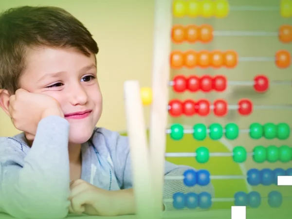 Rapaz sorridente, com o queixo apoiado na mão, a olhar para Explicações de Matemática 1.º Ano. Pacote de Horas em sala de aula.