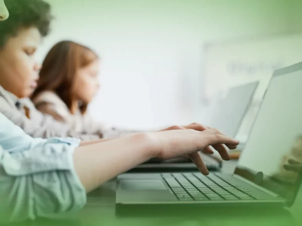Dois alunos focaram-se em Explicações de Tecnologias de Informação e Comunicação (TIC) 7.º Ano . Pacote de Horas em uma sala de aula, com quadro branco desfocado ao fundo.