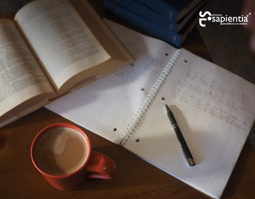 Uma xícara de café e um livro aberto sobre uma mesa.