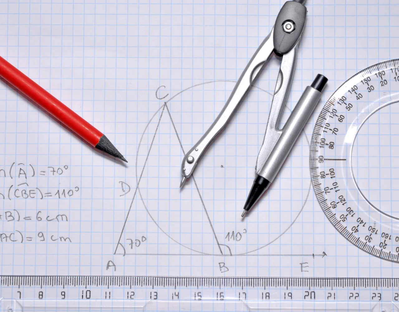 Uma imagem mostra uma geometria definida em papel milimetrado, contendo um lápis vermelho, um compasso de metal, uma caneta preta, um transferidor e uma régua, com um diagrama geométrico envolvendo ângulos e um círculo.
